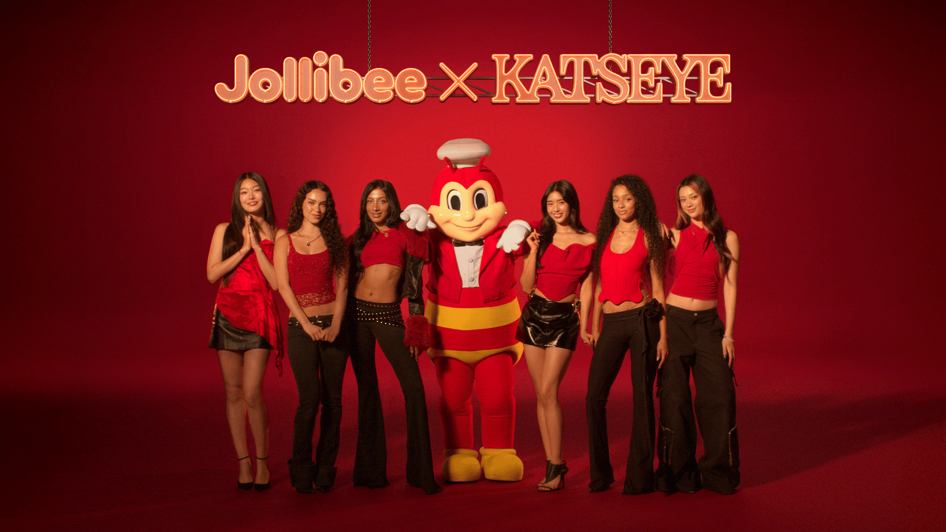 Jollibee mascot and KATSEYE standing on a red background with Jollibee x KATSEYE text